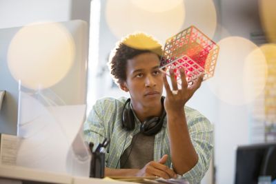 Man holding a cube structure in his hand and studying it, Experience Management | DXC Technology 